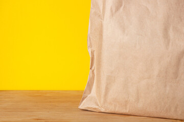Brown craft paper eco bag on bright yellow background. Delivery concept
