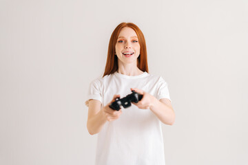 Studio portrait of cheerful attractive young woman playing video game with controller looking at...