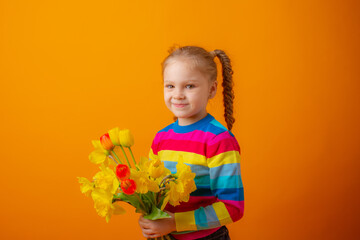 a cute little girl in a multicolored sweater holds a bouquet of spring flowers on a yellow background