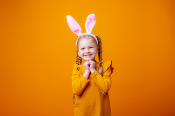 cute little girl with Easter bunny ears,on a yellow background, shows different emotions, joy, surprise, happiness, dreaming,