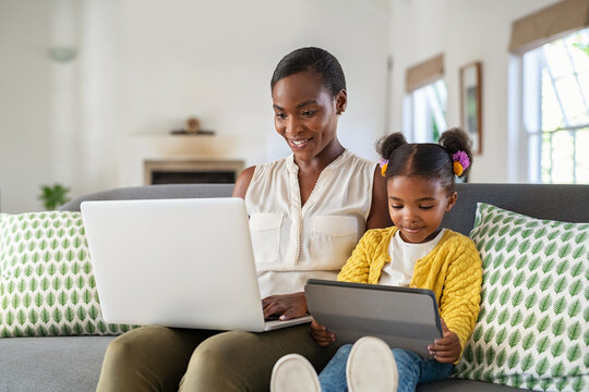 Woman working from home while her daughter using digital tablet