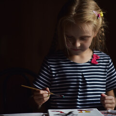 a blonde girl paints with a brush on canvas