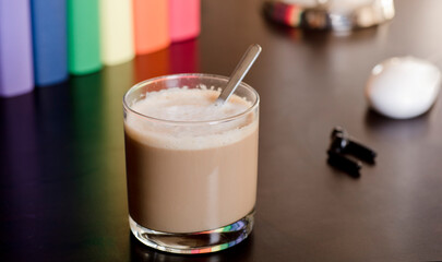glass cup with hot latte on purple work desk, headphones and books with lgbt movement colors
