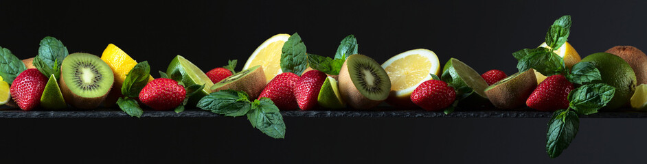 Fototapeta na wymiar Fruits close-up a colorful assorted mix of strawberry, lime, lemon, kiwi, and mint.