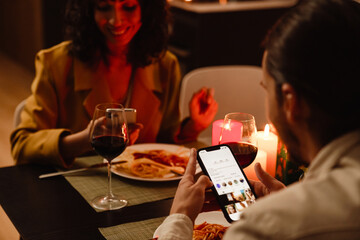 White couple using mobile phones during date in restaurant