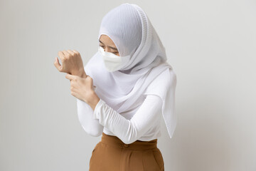 Young muslim woman patient with face mask holding wrist or hand with pain, sickness concept CTS,...