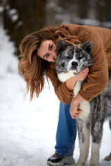 Love to the animals. Young woman playing in the snow with a husky dog. Pet lover. Dog - human s friend concept.