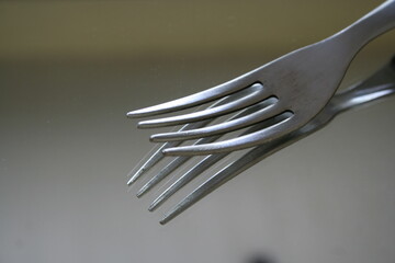 Tenedor o trinchante de acero brillante para comer, presenta una bonita ilustraciòn de diseño con sus puntas afiladas y su reflejo en la mesa de cocina