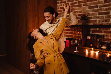 White romantic couple dancing while drinking wine at home