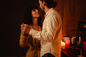 White romantic couple looking at each other while dancing at home