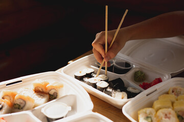 Delivery sushi rolls in plastic food container. Japanese cuisine. Set of sushi rolls in disposable containers. Food delivery service and takeout concept