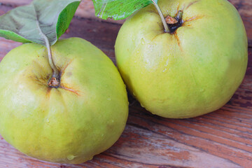 close-up, two fresh quince with leaves on a wooden board, top view