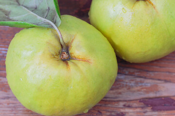  macro, fresh quince with a leaf on a wooden board, side view