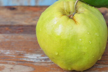 macro, fresh quince with a leaf on a wooden brown board, side view