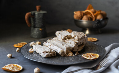 Halwa with hazelnuts, caffe pot, dry fruits, nuts, grey napkin on dark grey background