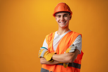 Confident smiling teen boy wearing orange hard hat against yellow background