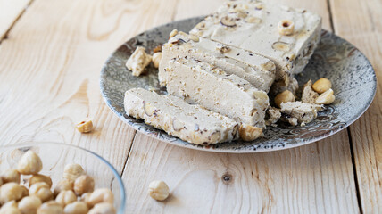 Halwa with hazelnuts on grey plate and wooden background 