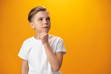 Teenager boy thinking looking away isolated on yellow background