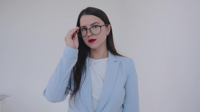 Serious young business lady approaches the camera and puts on glasses. Career and success concept. Feminism. Woman power