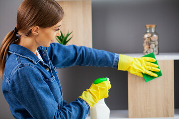 Pretty woman in uniform with supplies cleaning in office