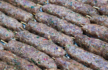 Raw minced meat on wooden sticks ready for grilling.