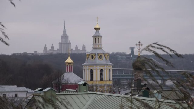 scenic domes of orthodox church and Moscow State University building on background by windy autumn day
