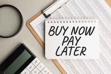 Notepad with text BUY NOW PAY LATER, with black marker on white background