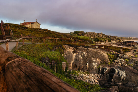 Intentional blur of wooden rail fence on footbridge along the cliffs of S&atilde;o Paio beach with chapel in hermitage, Labruge - Vila do Conde PORTUGAL