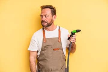middle age man feeling sad, upset or angry and looking to the side. gardener hose concept