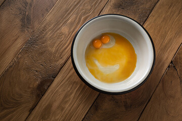 Raw broken for breakfast double yolk chicken egg smiling at you from metal bowl