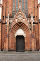 Old, brown metal door on the  church building, surrounded with bricks,  in the city center of Warsaw