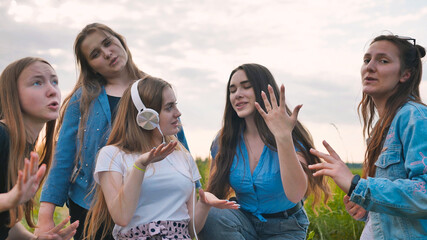 A group of girls of friends are listening to music on headphones and dancing to a friend.