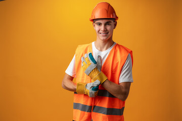 Confident smiling teen boy wearing orange hard hat against yellow background