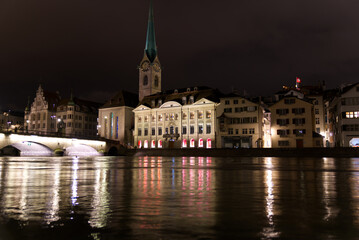 Medieval old town of Zürich with protestant church Women's Minster and river Limmat on a rainy and snowy winter Friday night. Photo taken January 7th, 2022, Zurich, Switzerland.