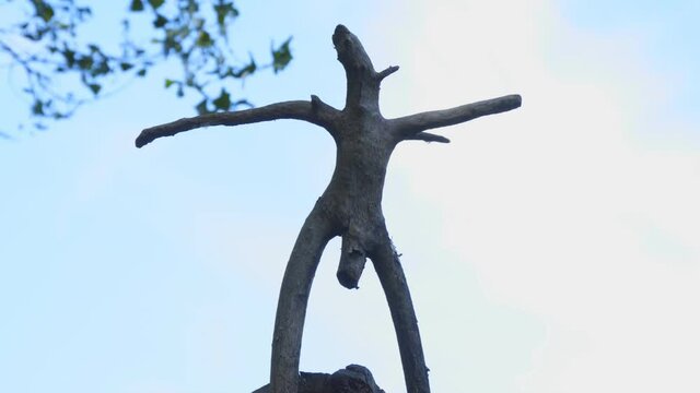 Silhouette wooden snag in the form of a pagan idol against the cloudy sky. Camera zoom in