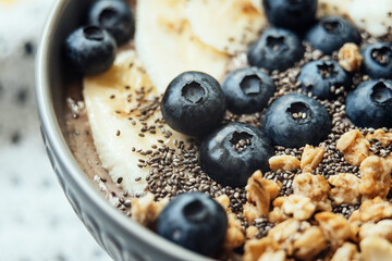 Healthy breakfast berry smoothie bowl topped with banana, granola, Blueberries and chia seeds with copy space. delicious blueberry smoothie bowl. Healthy vegan raw food. - obrazy, fototapety, plakaty