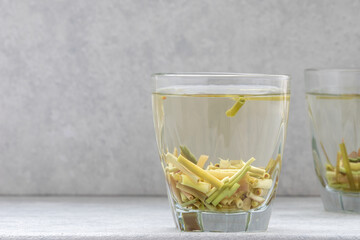 Tea beverage of dry cut lemon grass herb in glass cup.