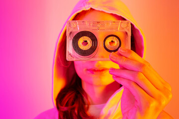 Teenager girl holding old cassette tape - pink and orange background, pop art style