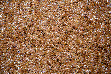 The background of flax seeds (Latin Línum usitatíssimum) is brown with beautiful seed shapes. Food cereals are healthy foods.