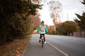 Rear view on child girl with backpack riding a bicycle