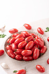 Fresh cherry tomatoes in a basket with spices.