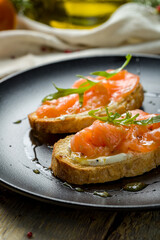 Bruschetta with salmon and cheese on black plate macro close up