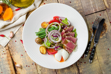 Nicoise with tuna, poached egg and vegetables on wooden table top view