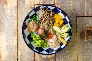 scallop poke with avocado, chukka, edamame; tomatoes, mango and boiled rice top view on wooden table