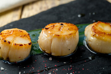 grilled scallop on black stone macro close up