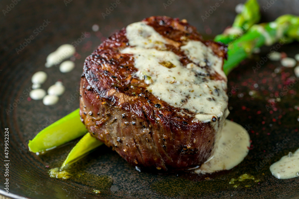 Sticker roast beef Steak with asparagus on black plate on wooden table macro close up