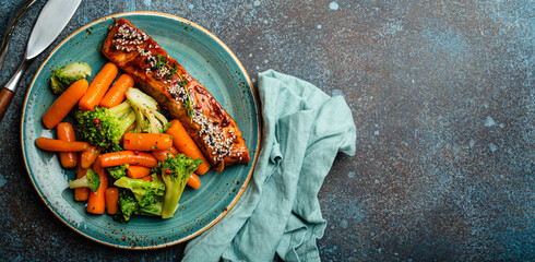 Grilled salmon fillet steak in teriyaki sauce with roasted vegetables carrot and broccoli on plate...