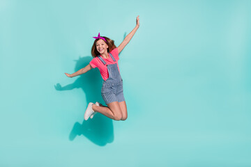 Full size photo of cute kid girl jump playing bird fly wear t-shirt shorts isolated on cyan color background