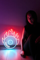 Beautiful girl with neon signs. Orange and blue neon vinyl record. Trendy style. Neon sign. Custom neon. Neon concept. Modern style. Neon sign. Party background. 