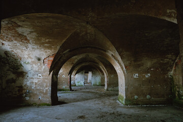 Abandoned building. The interior of the old building with rounded arches and unusual ceiling vaults. Shabby old brick, sprinkled with plaster, grundy interior decoration with green fungus on the walls